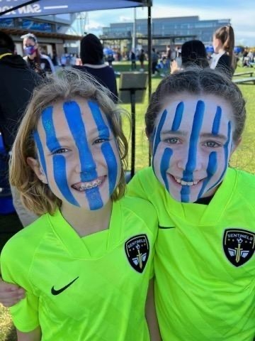Two Sentinels teammates in blue face paint on a club match day