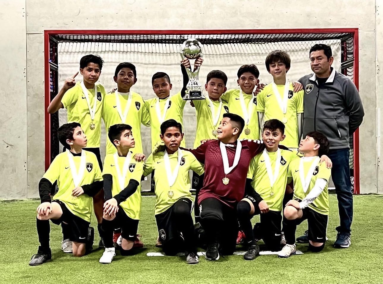 Sentinels boys competitive futsal champions with trophy, medals, and coach indoors